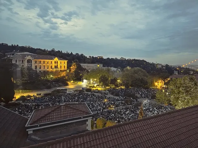 İstanbul'da akşam saatlerinde ağaçlar ve tarihî binalar arasındaki açık hava festival alanını dolduran kalabalık