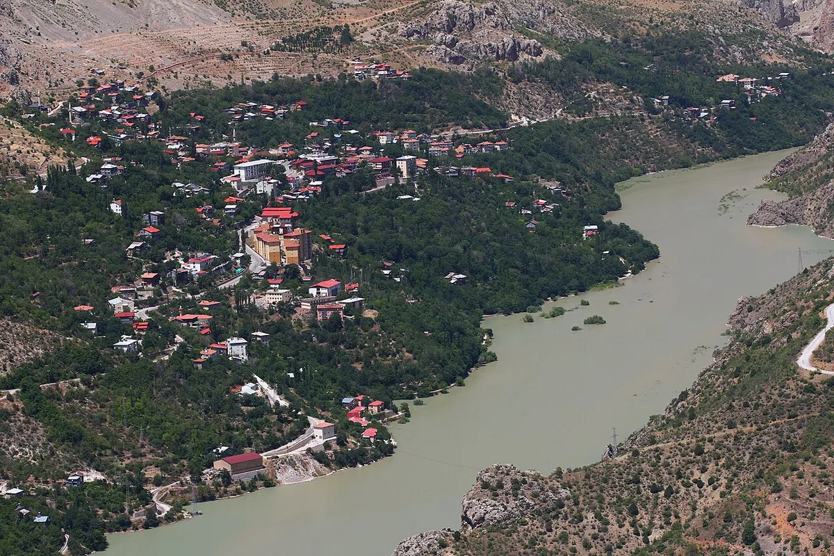 Kemaliye ilçesinin vadi yamacına yayılan kırmızı çatılı evleri ve yanından akan Fırat